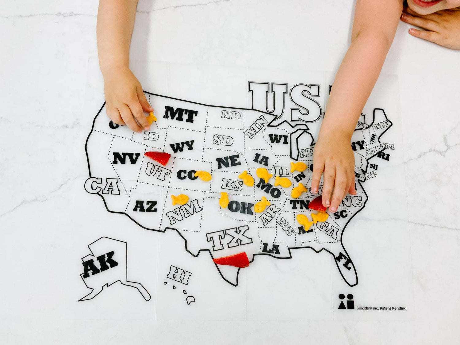 Child coloring on a GoSili silicone placemat featuring a U.S. map with washable markers.
