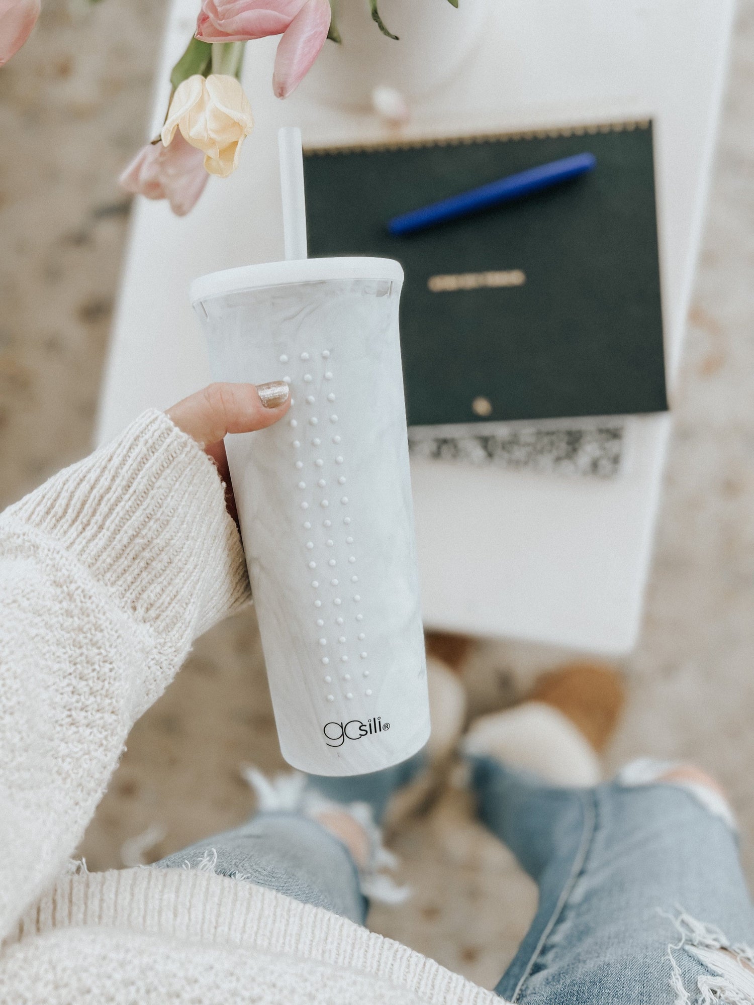 Woman enjoying a smoothie in a calacatta-colored 24oz silicone tumbler with straw